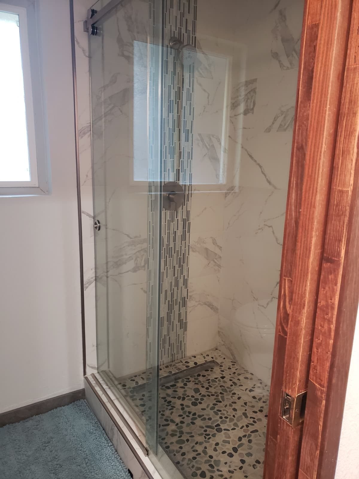 Marble tile shower with pebble floor